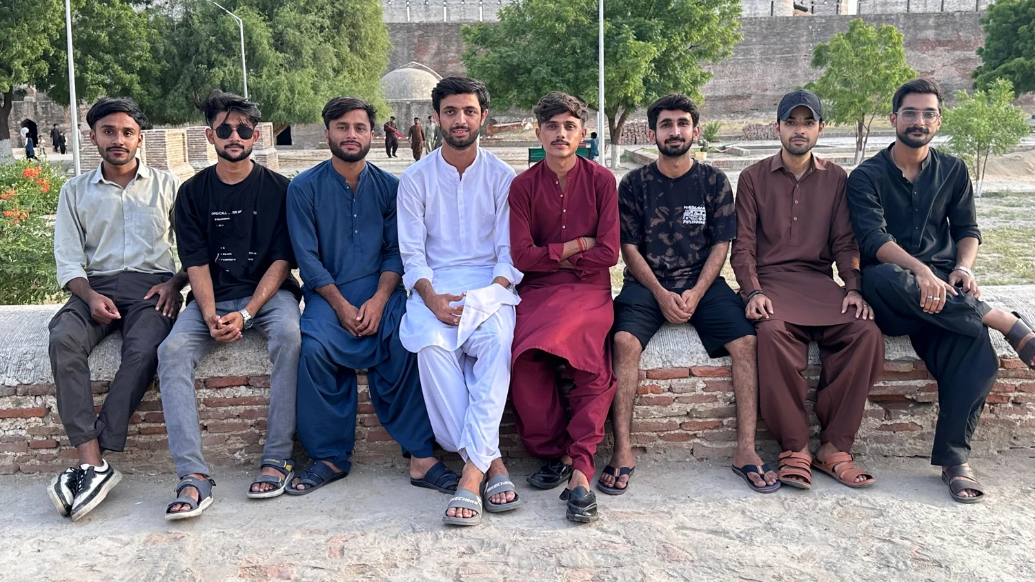 Friends seated together on a low wall outdoors
